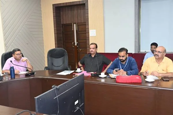 बैठक कक्ष में मेज के पास बैठे अधिकारी रक्तदान अभियान की तैयारियों पर चर्चा करते हुए