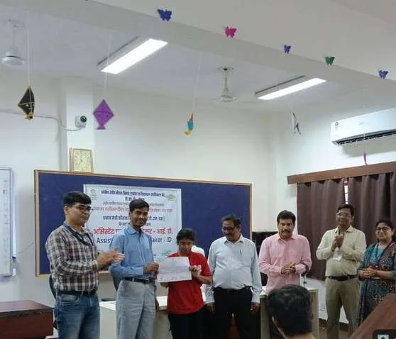 कक्षा में बैनर के सामने एक प्रशिक्षु को प्रमाणपत्र देते प्रतिनिधि